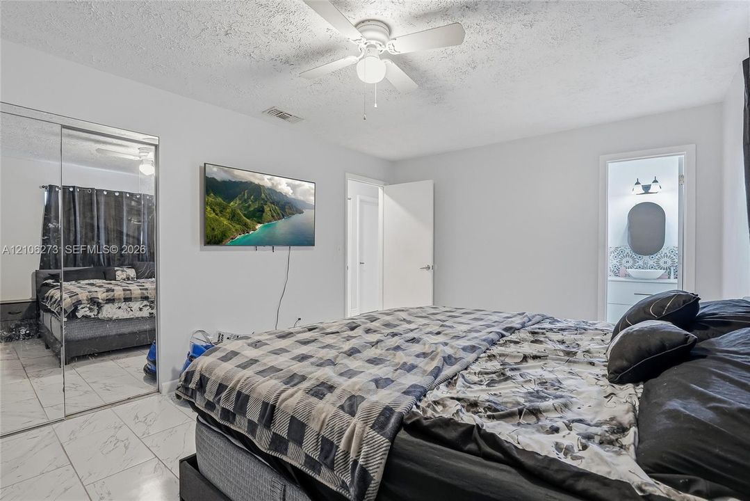 Bedroom featuring white tile flooring, ceiling fan, and mirrored sliding closet doors