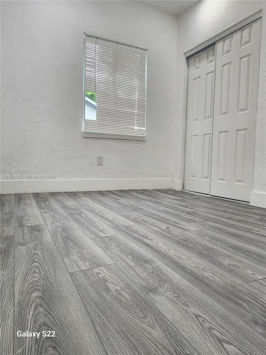 Wood-finish flooring, white textured walls, and dual-panel closet doors