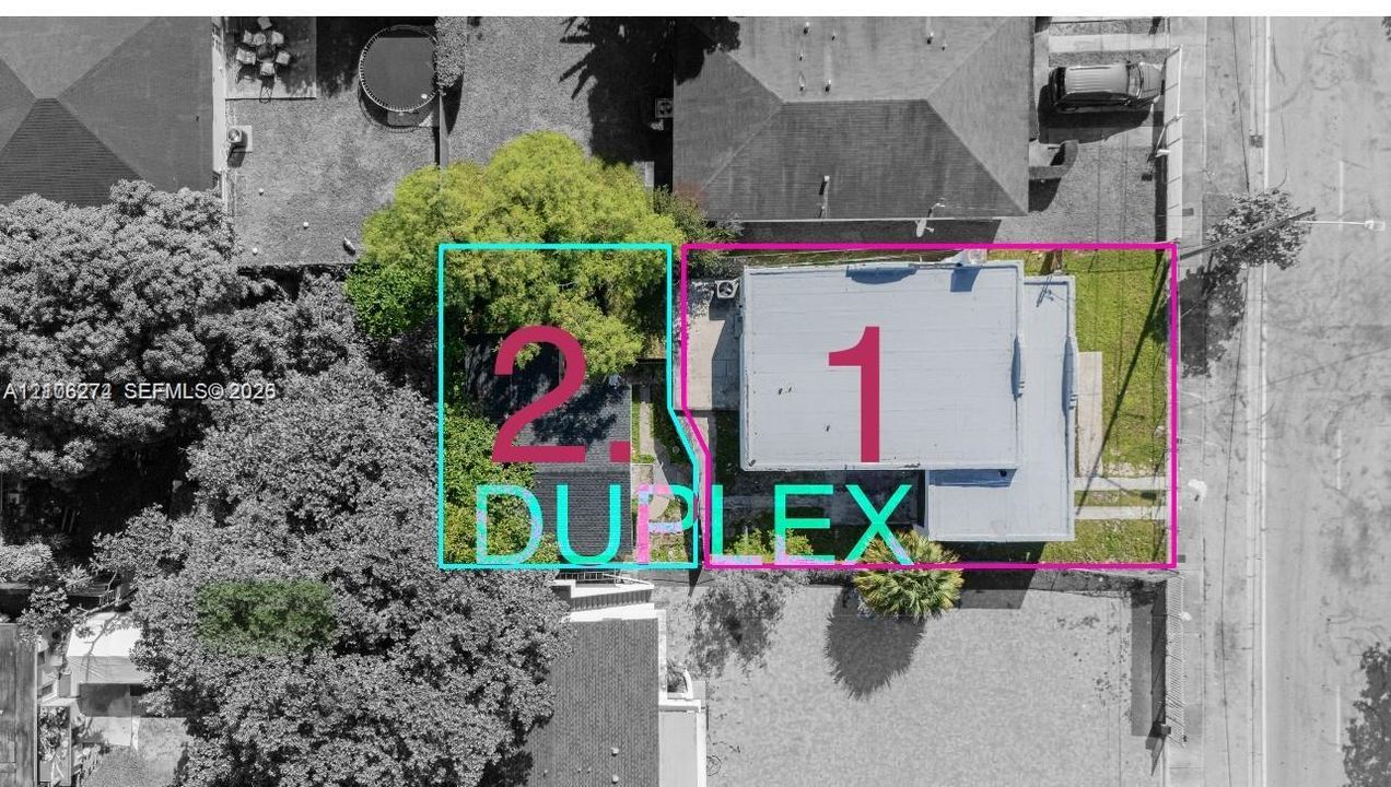 Aerial perspective of the property featuring a rectangular structure, dedicated off-street parking areas, and mature landscaping