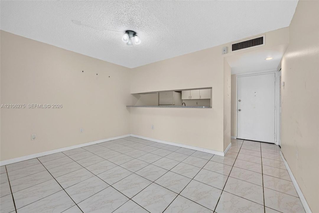 Ceramic tile flooring, kitchen pass-through window with a stone-finish countertop, ceiling-mounted light fixture, and solid-core interior entry door