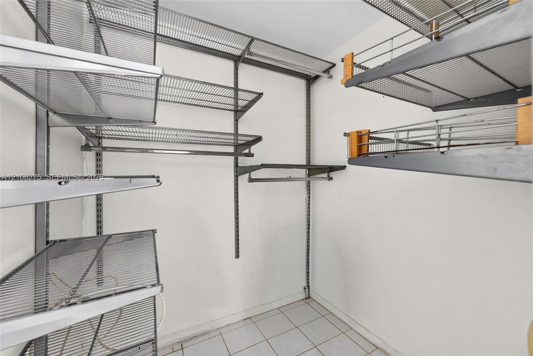 Storage area featuring adjustable metal shelving units, integrated wire racking, and tile flooring