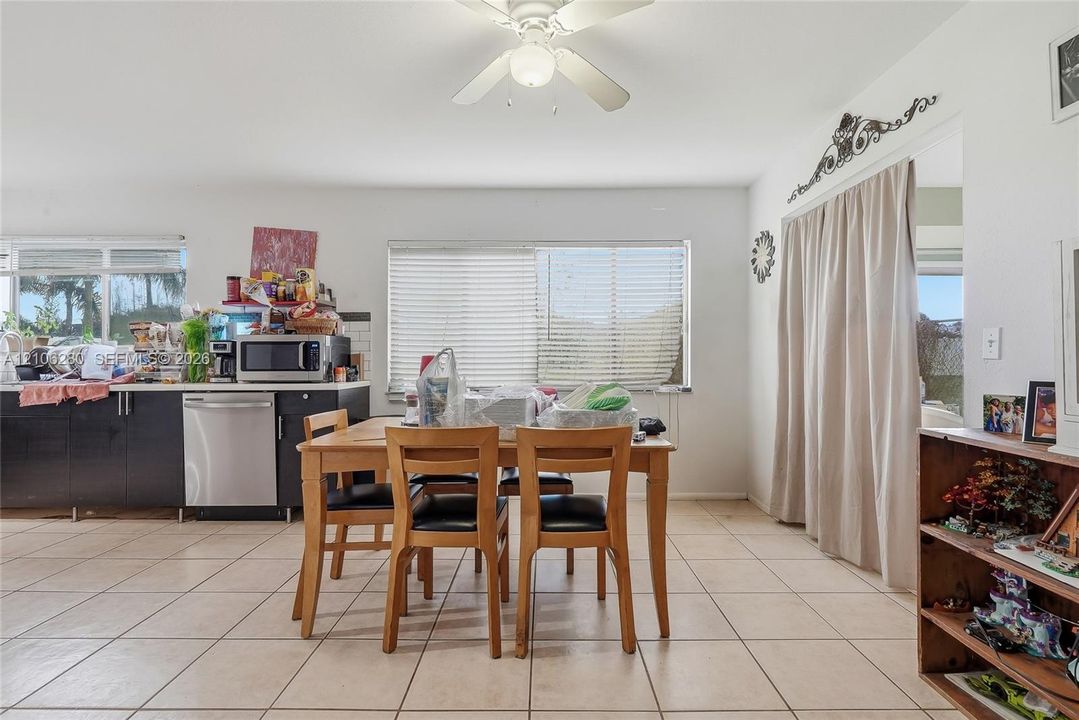 Kitchen featuring dark cabinetry, stainless steel dishwasher, tile flooring, and a ceiling fan