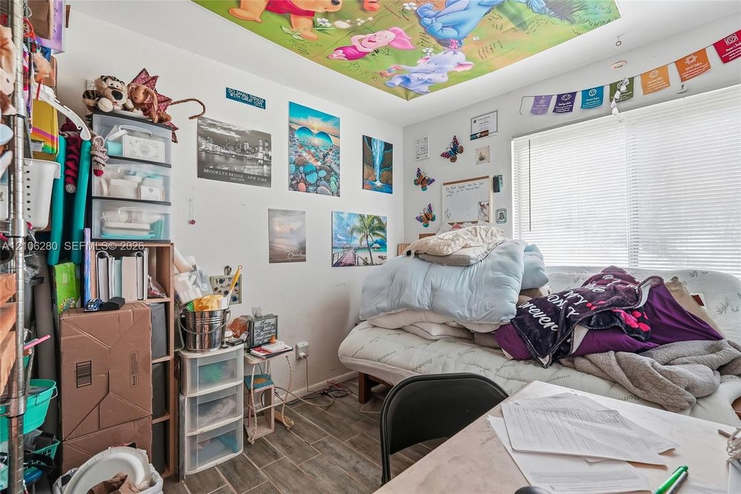 Wood-finish tile flooring and a window with horizontal blinds