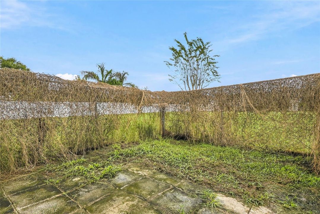 Outdoor space featuring a paved stone patio and a wire mesh perimeter fence