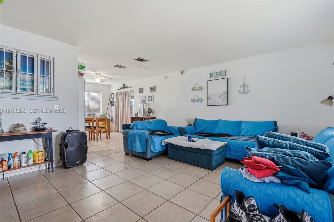 Open-concept living space featuring large-format ceramic tile flooring, neutral walls, recessed ceiling lighting, and a multi-pane decorative window accent