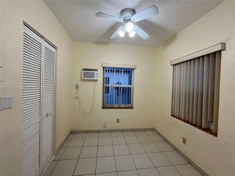 Room featuring tile flooring, louvered bi-fold closet doors, a ceiling fan with integrated lighting, and vertical window blinds