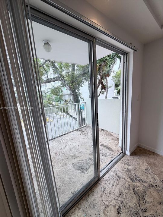 Sliding glass doors opening to a private balcony with stone-finish flooring and a metal railing