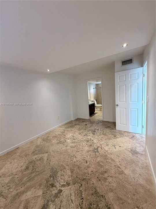 Stone tile flooring featuring a natural texture, recessed ceiling lighting, and a multi-panel interior door