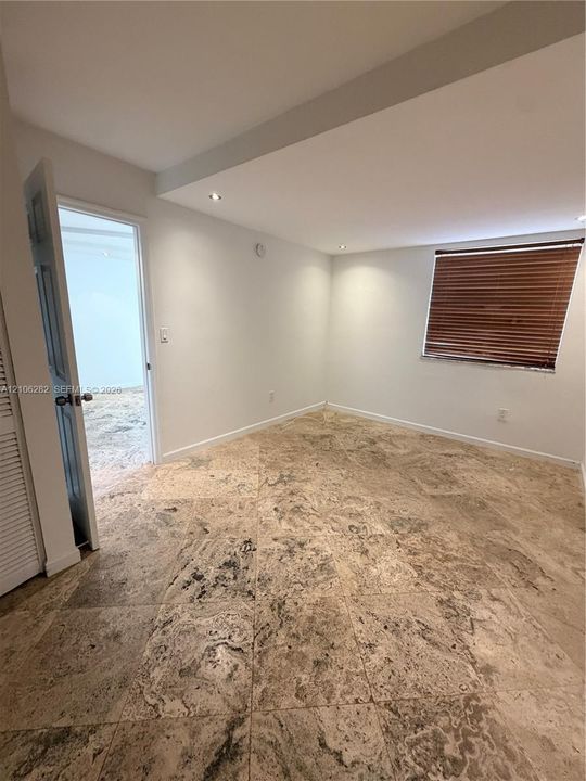 Interior space featuring stone-tile flooring, recessed ceiling lighting, and a louvered closet door