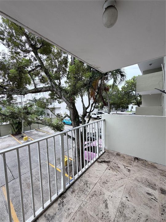 Covered balcony featuring stone-finish flooring, a white metal railing, and an integrated ceiling light fixture