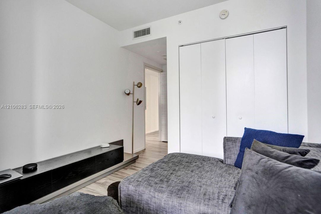 Built-in wall-mounted shelving, wood-finish flooring, and dual-panel closet with matte hardware