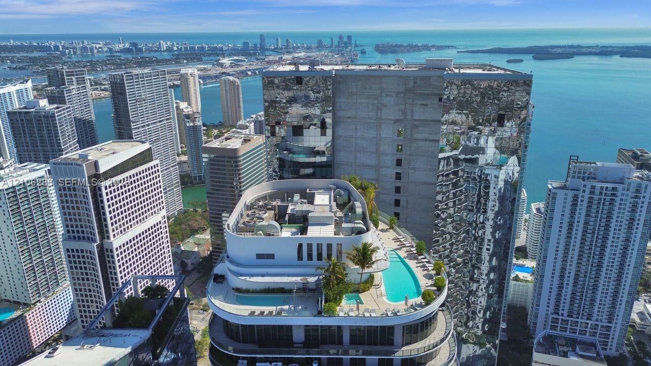 Rooftop terrace featuring multiple swimming pools, integrated landscaping, and panoramic water and city skyline surroundings