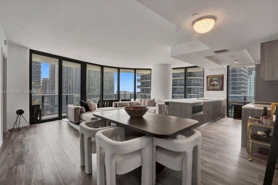 Open-concept living space featuring floor-to-ceiling windows, wood-finish flooring, a kitchen island with stone countertops, and recessed lighting