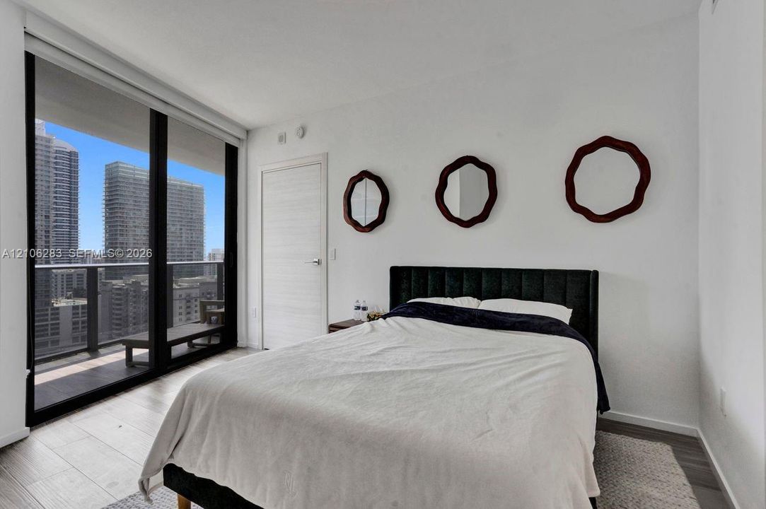 Floor-to-ceiling sliding glass door, private balcony, wood-finish flooring, and crisp white wall finishes
