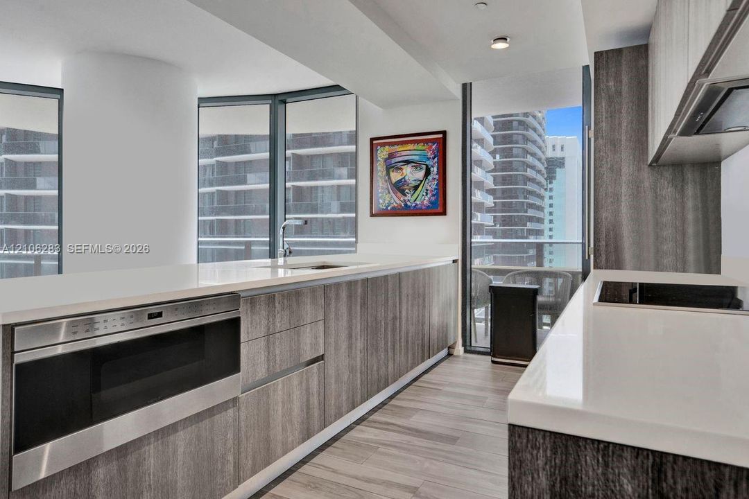 Kitchen featuring wood-finish cabinetry, stone-surface countertops, built-in stainless steel microwave, integrated stovetop, and floor-to-ceiling windows