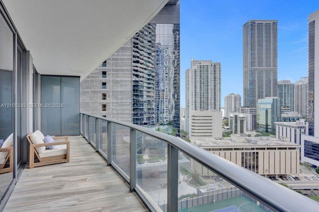 Covered balcony featuring tile flooring, metal railings, and glass partition panels