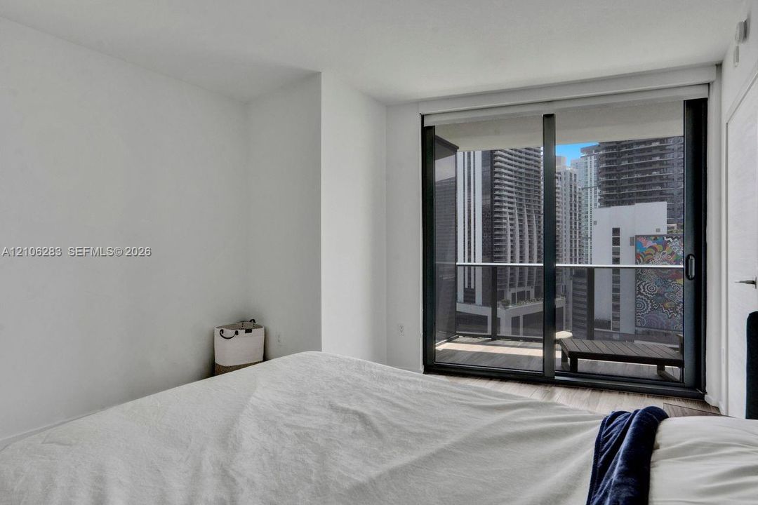 Floor-to-ceiling sliding glass door, private balcony with metal railing, and wood-finish flooring
