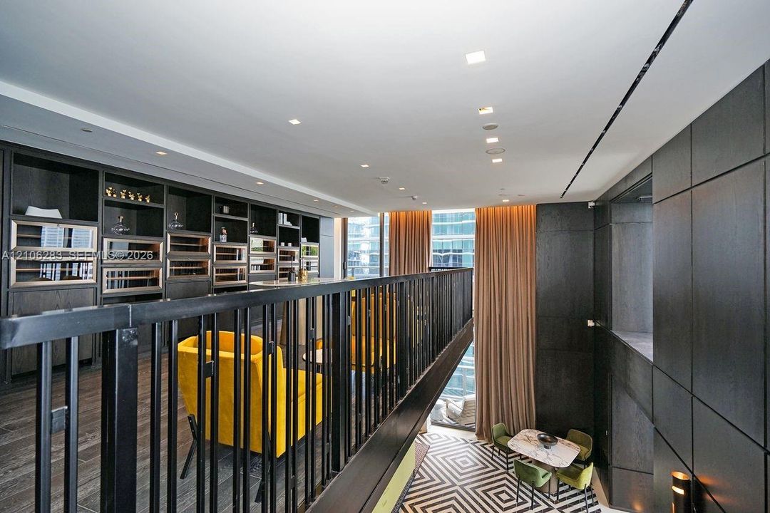 Custom built-in cabinetry featuring integrated temperature-controlled storage, dark wood-finish wall paneling, metal railing, and recessed ceiling lighting