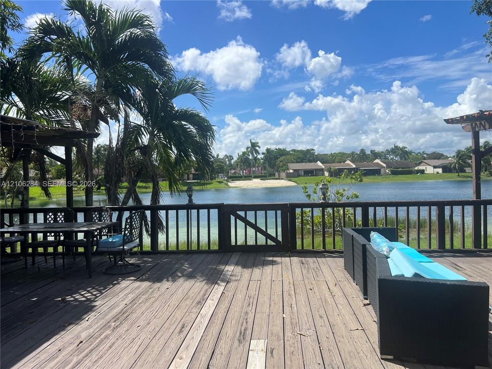 Expansive wooden deck featuring perimeter railing, overhead pergola structures, and direct water frontage