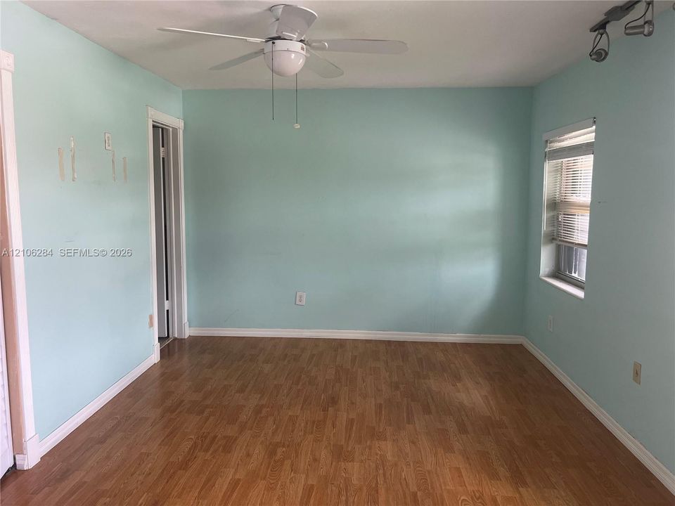 Interior room featuring wood-finish flooring, a ceiling fan with integrated light fixture, and adjustable track lighting