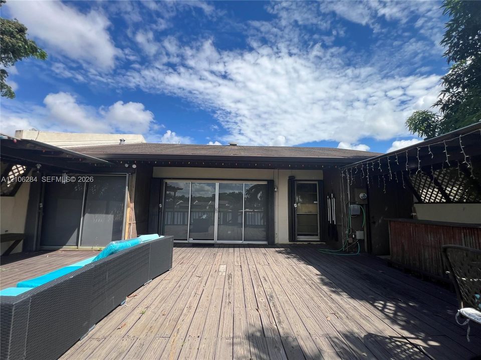 Spacious wooden deck featuring sliding glass doors and covered patio areas