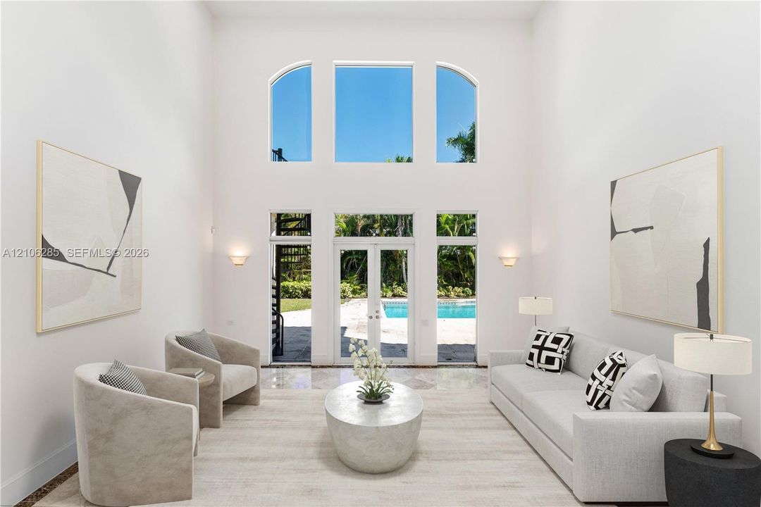 Double-height ceilings, arched transom windows, floor-to-ceiling glass French doors, stone flooring, and built-in wall-mounted light fixtures