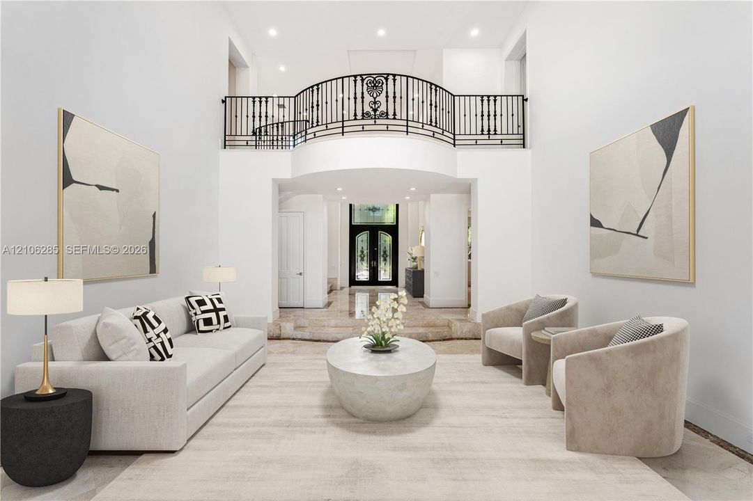 Double-height ceiling entryway with a Juliet balcony, custom wrought-iron railing, recessed lighting, and polished stone flooring