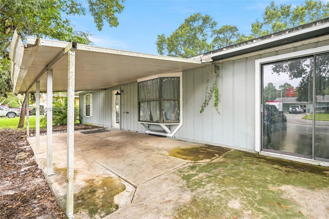 Covered concrete patio with vertical siding, bay window, and large sliding glass door