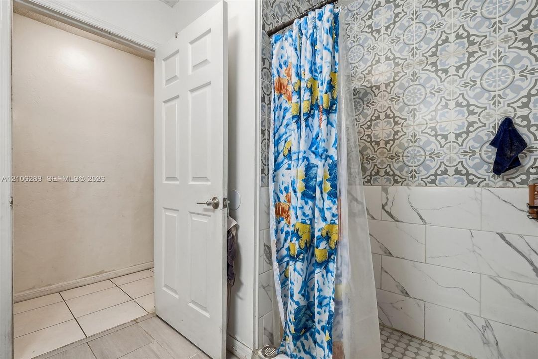 Shower surround featuring patterned tile accents, subway-style wall tile with vein detailing, and hexagonal floor tile