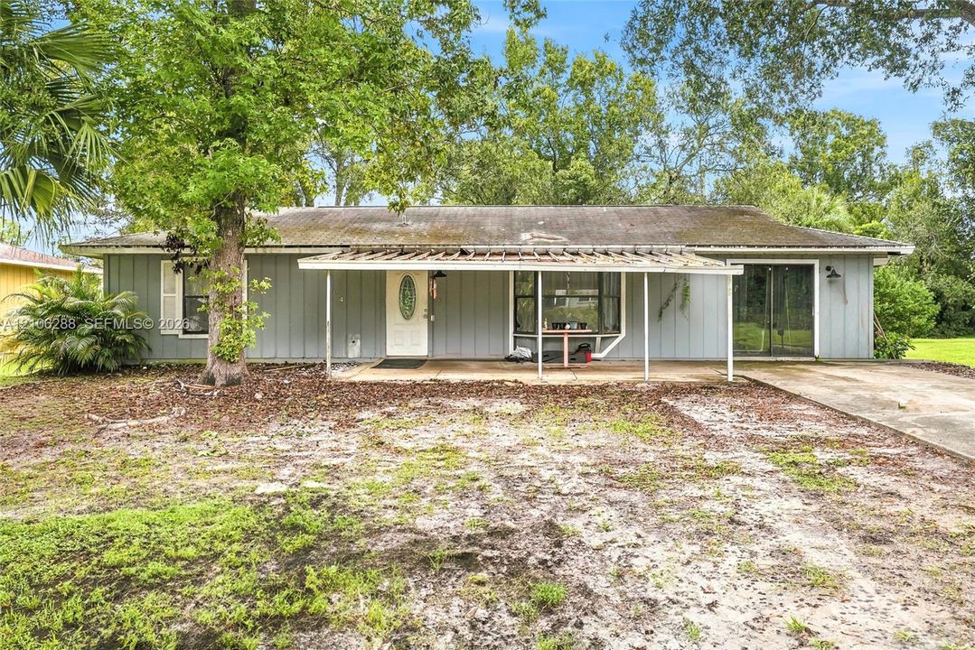Single-story exterior featuring light-toned vertical siding, a covered front porch, a bay window, and a concrete driveway