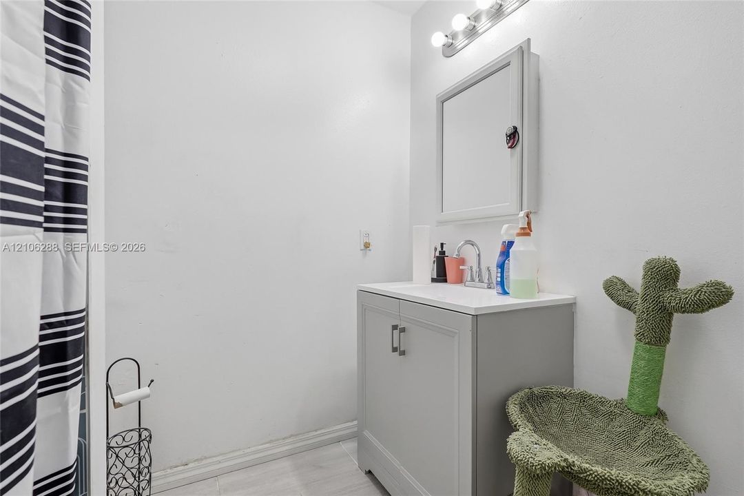 Bathroom vanity featuring a solid-surface countertop, dual-door gray cabinet, and wall-mounted medicine cabinet with a three-light fixture