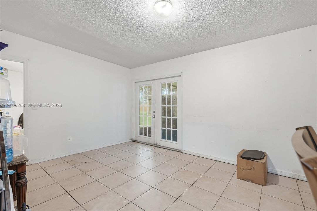 Room featuring large-format neutral tile flooring and double glass-paned doors