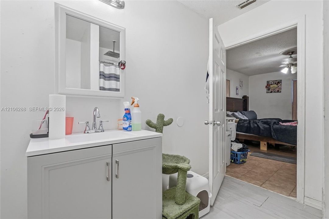 Bathroom featuring a grey vanity cabinet with a white countertop, polished chrome faucet, medicine cabinet with a mirrored door, and wall-mounted light fixture