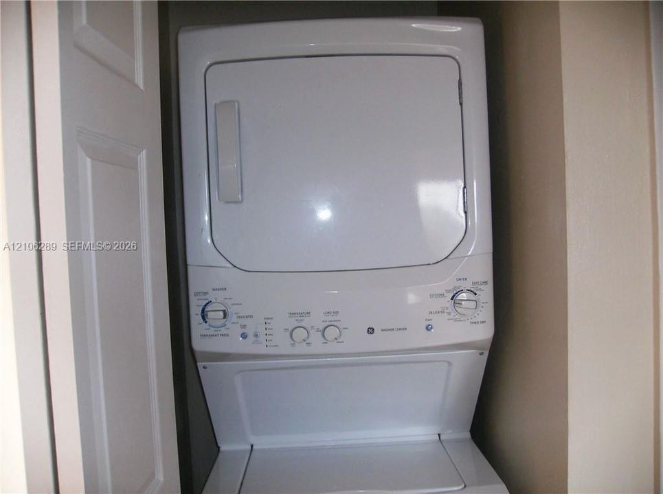 White stackable washer and dryer unit with rotary controls and top-loading basin