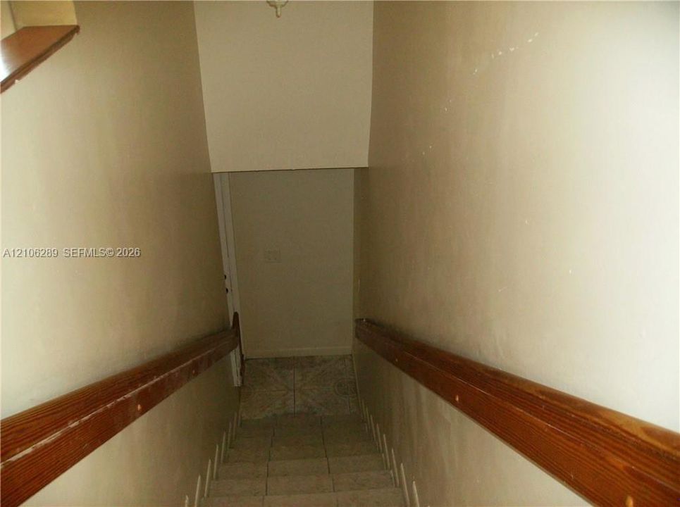 Staircase featuring tiled treads and dual wood-finish handrails