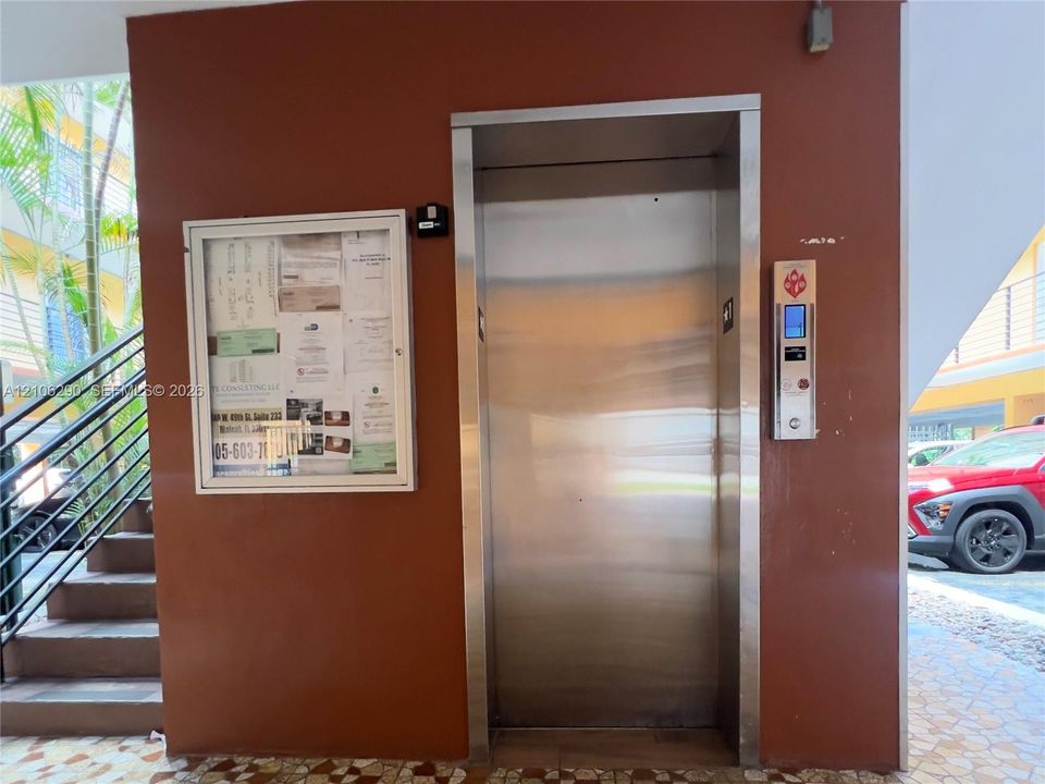 Stainless steel elevator with a digital interface panel, mounted on a solid-surface wall