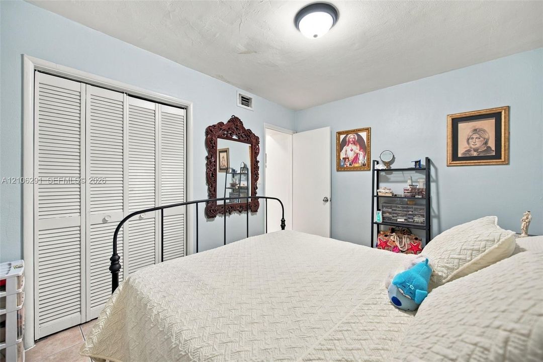 Room featuring light blue walls, white louvered-panel closet doors, and a flush-mount ceiling light fixture