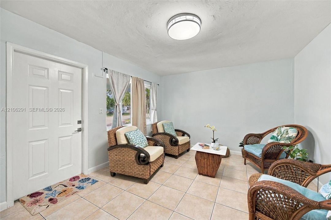 Interior space featuring neutral wall tones, large-format ceramic tile flooring, a six-panel exterior entry door, and a flush-mount circular ceiling light fixture