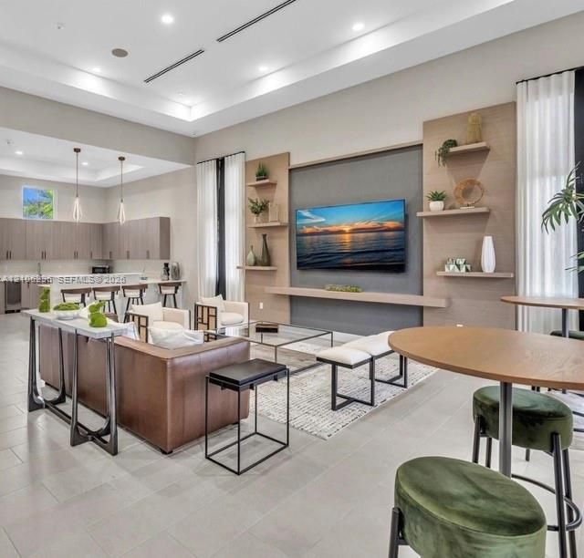 Open concept area featuring high ceilings with recessed lighting, tile flooring, and custom wood-paneled media wall with built-in shelving
