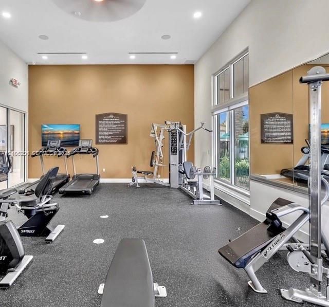 Fitness center featuring high ceilings, recessed lighting, expansive mirrored wall, rubberized flooring, and floor-to-ceiling windows