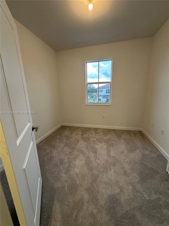 Neutral-toned interior space featuring wall-to-wall carpeting, a single-hung window with a muntin grid, and a raised-panel interior door
