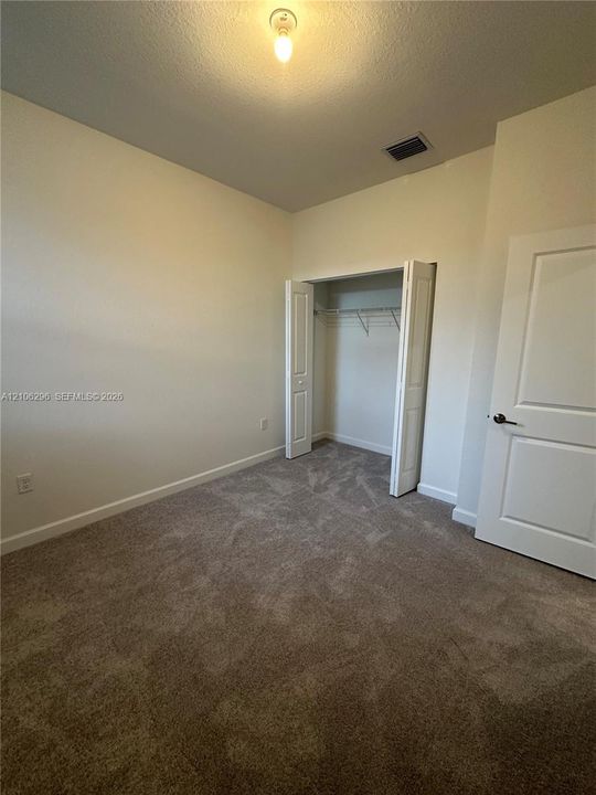 Neutral-toned carpeted flooring, wall-mounted interior door, and bi-fold closet doors with integrated wire shelving