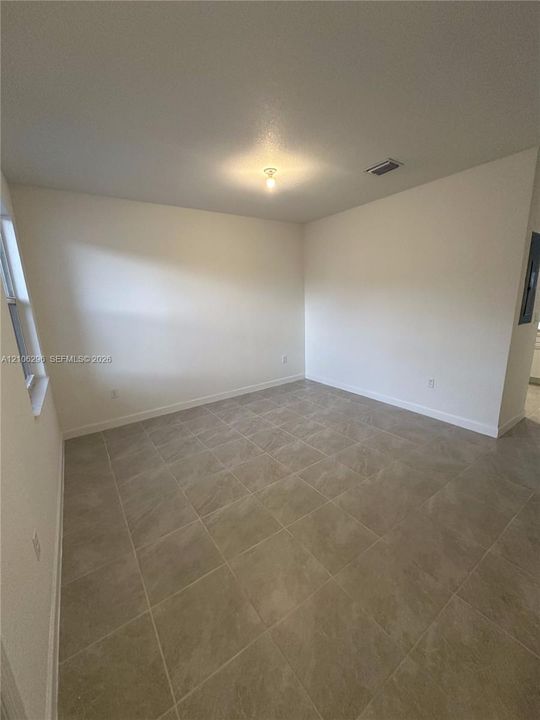 Neutral-toned interior space featuring large-format ceramic tile flooring, neutral wall paint, and a single-light ceiling fixture