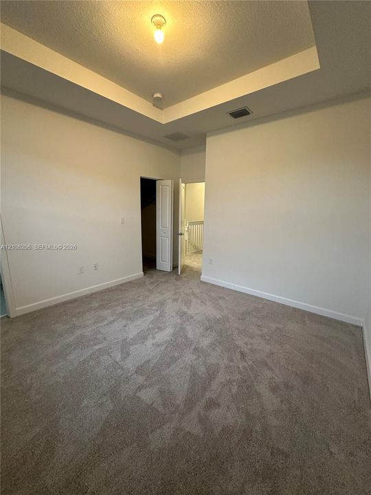 Room featuring a tray ceiling, wall-to-wall carpeting, and an interior door leading to a closet space