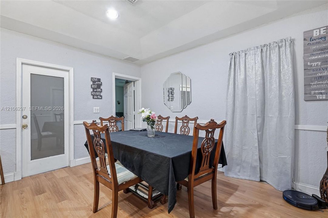 Tray ceiling, wood-finish flooring, and a single-light frosted glass exterior door with brushed metal hardware