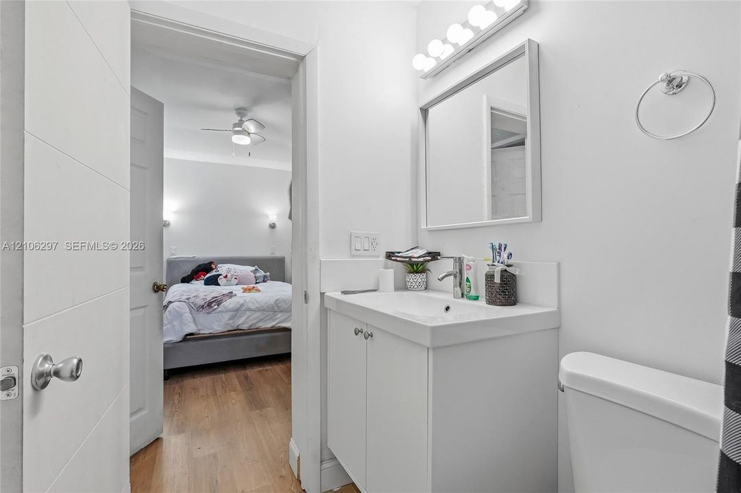 Bathroom featuring a white vanity cabinet, integrated sink, wall-mounted mirror, and multi-bulb light fixture