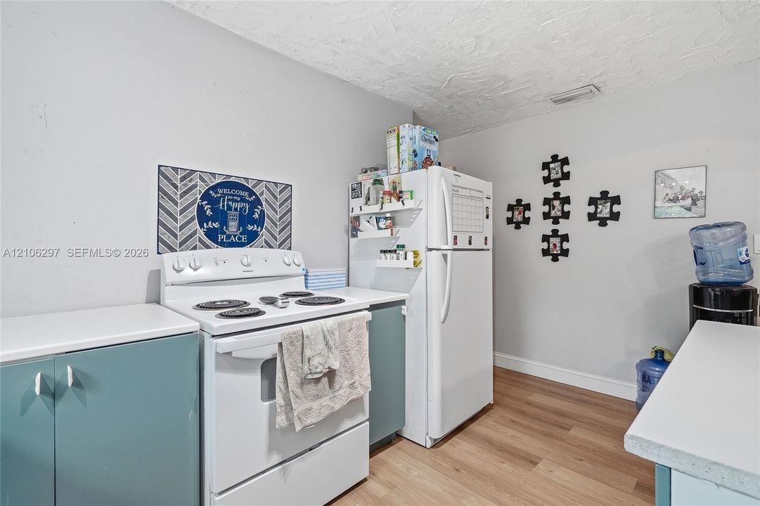 Kitchen featuring wood-finish flooring, white cabinetry, a freestanding electric range, and a top-freezer refrigerator