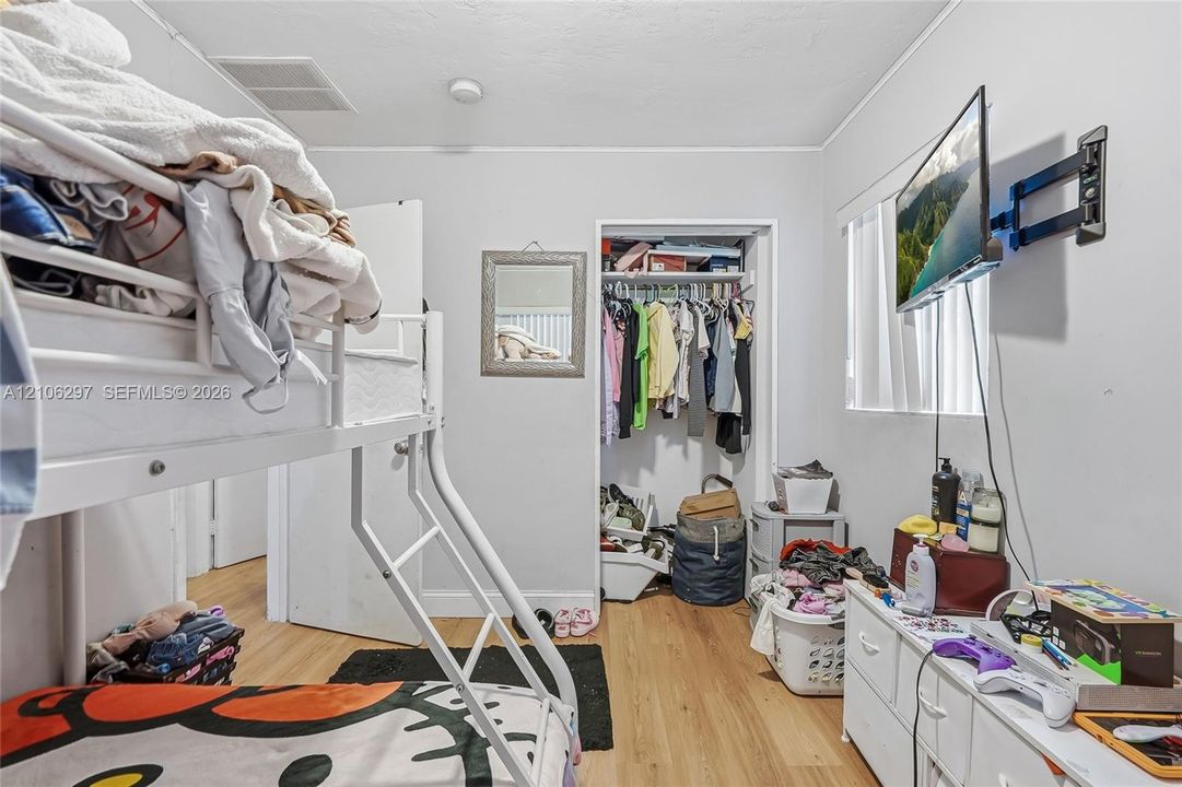 Room featuring wood-finish flooring and a walk-in closet with built-in shelving