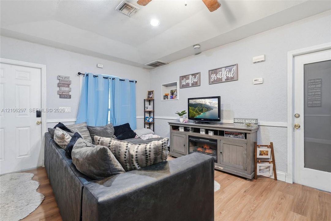 Living area featuring a tray ceiling, recessed lighting, wood-finish flooring, built-in wall niche, and chair rail molding