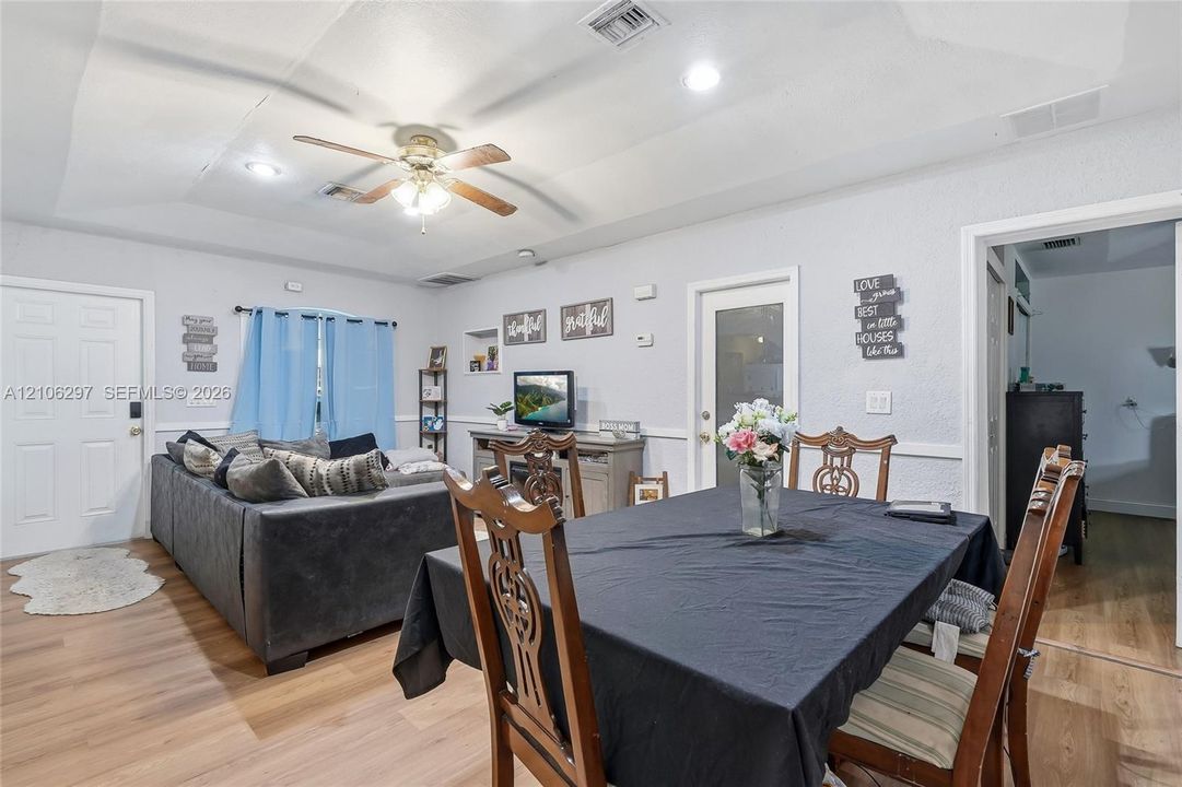 Tray ceiling featuring recessed lighting and a central ceiling fan, complemented by wood-finish flooring and chair rail molding